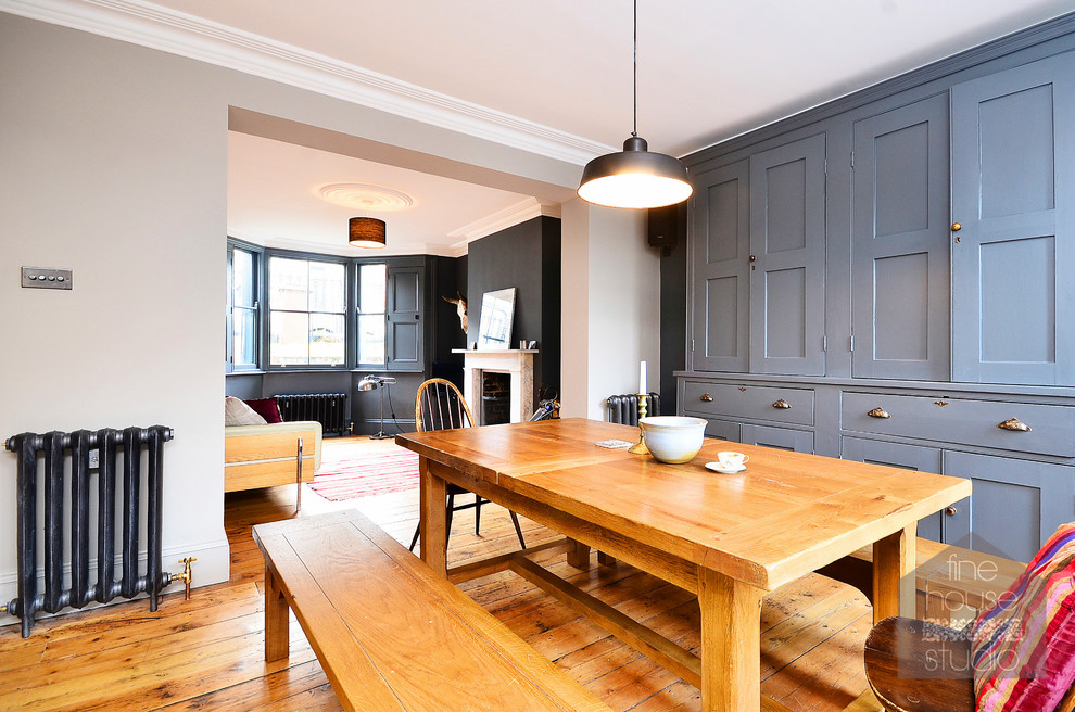 Aménagement d'une salle à manger ouverte sur la cuisine classique de taille moyenne avec un mur gris, un sol en bois brun, une cheminée standard et un manteau de cheminée en pierre.