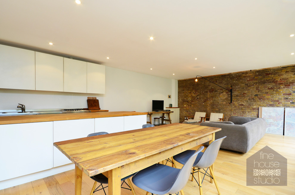 Idee per un'ampia sala da pranzo aperta verso la cucina industriale con pareti bianche e parquet chiaro