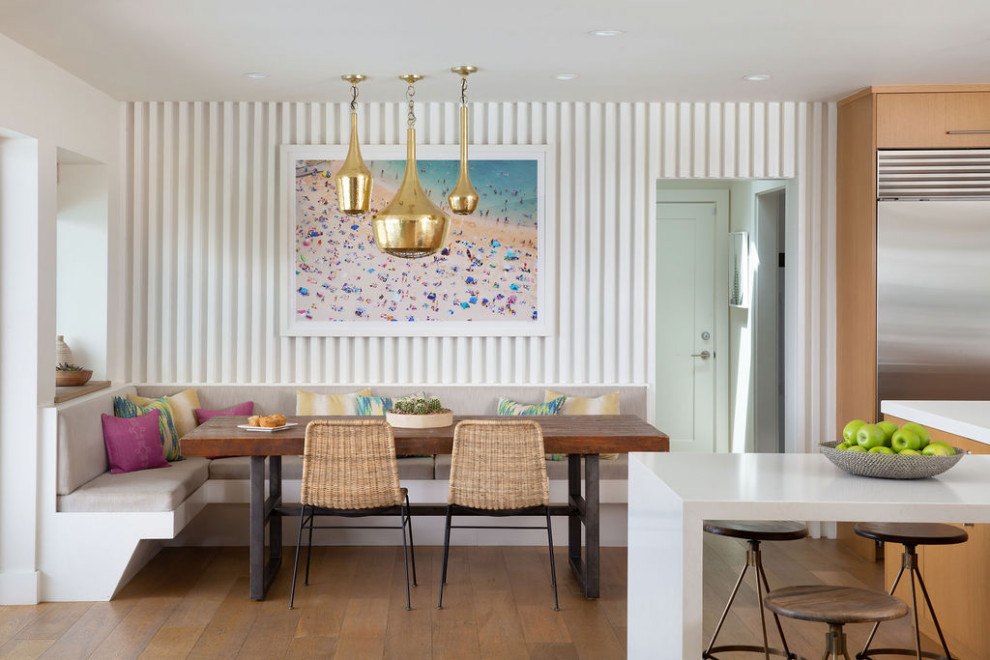Cette image montre une salle à manger ouverte sur la cuisine bohème avec un mur blanc, un sol en bois brun et un sol marron.