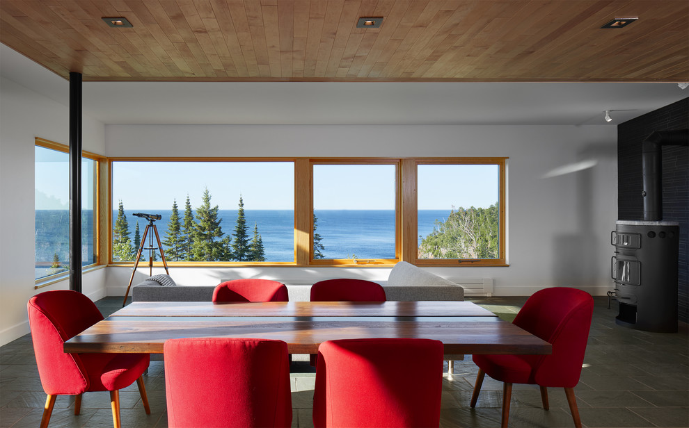 Diseño de comedor marinero con paredes blancas, suelo de pizarra, estufa de leña y suelo gris