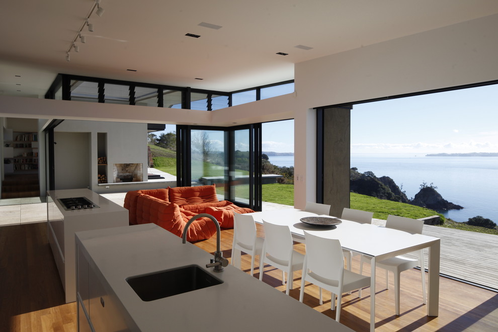 Idée de décoration pour une salle à manger ouverte sur le salon minimaliste avec un mur blanc et un sol en bois brun.