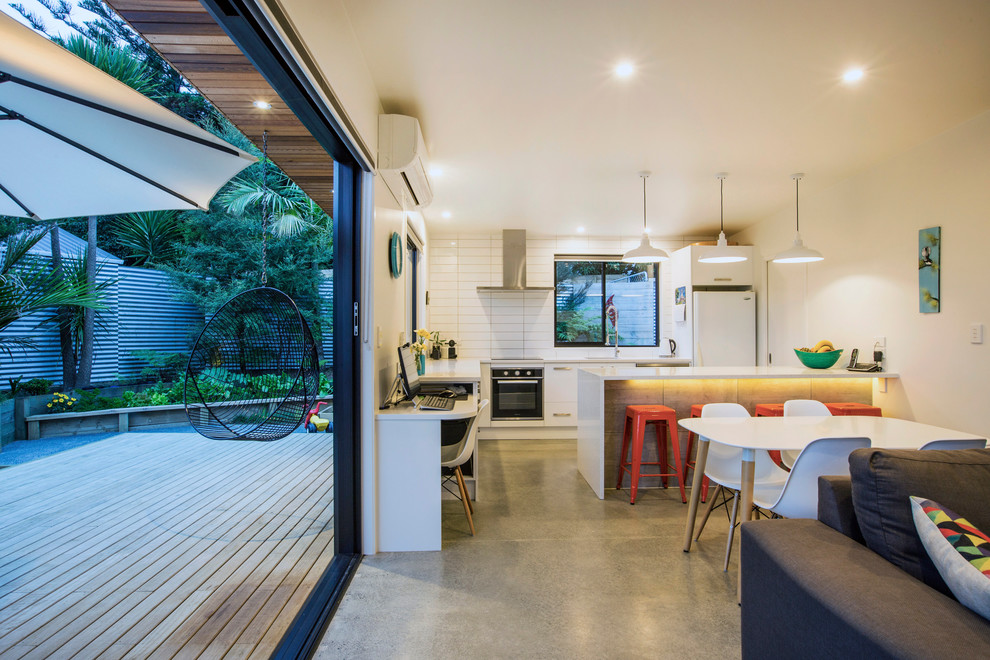 Kleine Moderne Wohnküche mit weißer Wandfarbe und Betonboden in Auckland