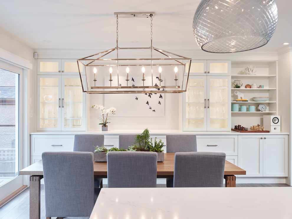 Immagine di una sala da pranzo aperta verso la cucina tradizionale di medie dimensioni con pareti bianche, pavimento in laminato e pavimento marrone