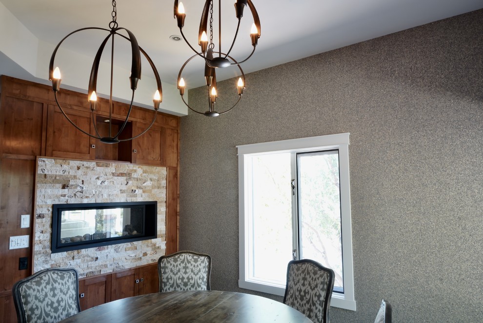 Idée de décoration pour une salle à manger craftsman fermée et de taille moyenne avec un mur gris, parquet foncé, une cheminée double-face, un manteau de cheminée en pierre et un sol gris.