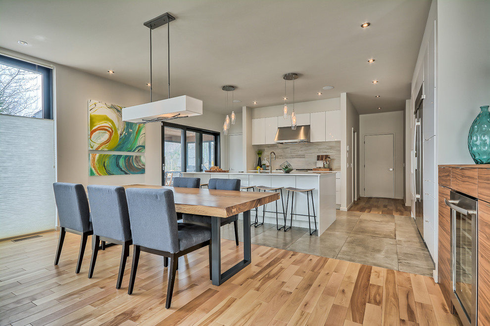 This is an example of a medium sized contemporary kitchen/dining room in Montreal with grey walls, light hardwood flooring, no fireplace and brown floors.