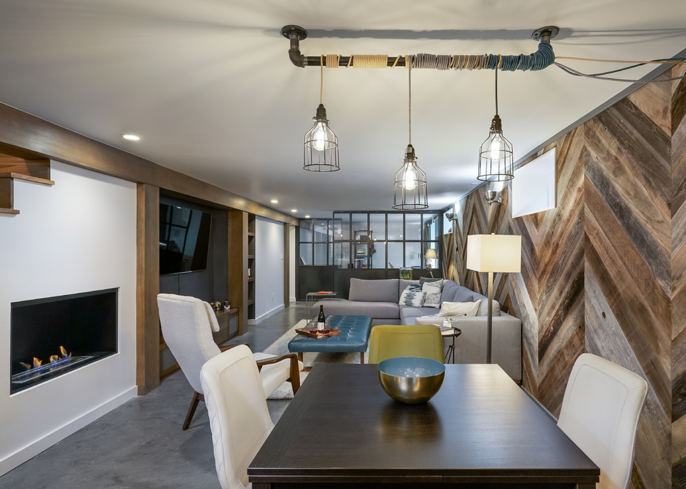 This is an example of an industrial open plan dining room in Portland with concrete flooring, a standard fireplace, grey floors, white walls and feature lighting.