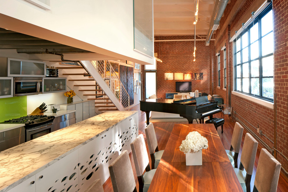 Aménagement d'une salle à manger ouverte sur le salon industrielle avec un sol en bois brun et un mur rouge.