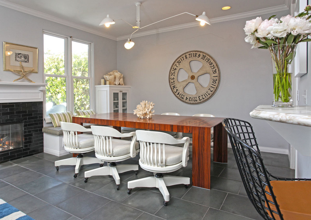 На фото: столовая в современном стиле с серыми стенами, стандартным камином и фасадом камина из кирпича