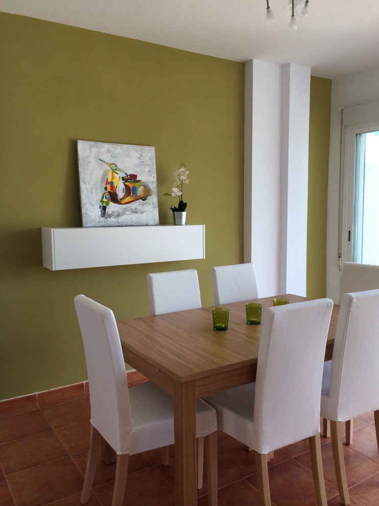 Foto di una sala da pranzo aperta verso la cucina design con pareti verdi e pavimento in terracotta
