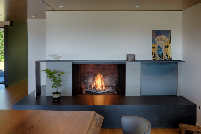 На фото: кухня-столовая среднего размера в стиле модернизм с серыми стенами, паркетным полом среднего тона, угловым камином, фасадом камина из бетона и коричневым полом