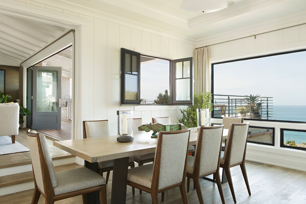 Beach style open plan dining room in Orange County with white walls and light hardwood flooring.