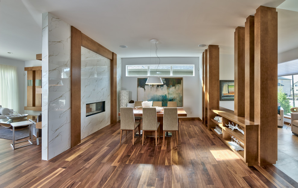 Immagine di una sala da pranzo design chiusa e di medie dimensioni con pareti bianche, pavimento in legno massello medio, camino bifacciale e cornice del camino piastrellata
