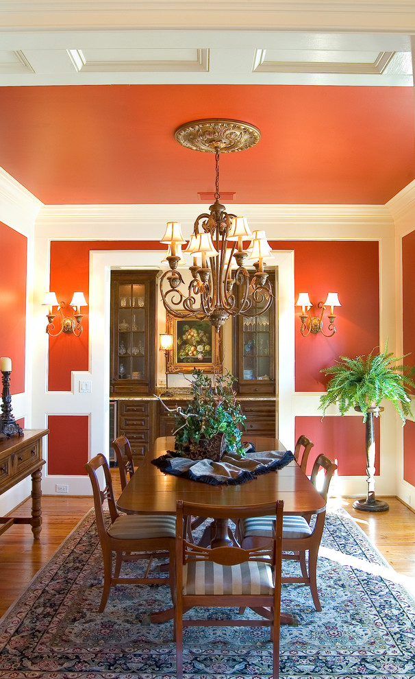 Example of a classic medium tone wood floor dining room design in Atlanta with red walls