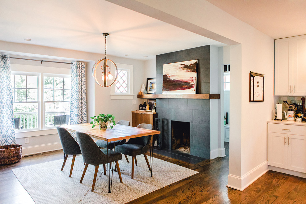 Exemple d'une salle à manger ouverte sur la cuisine chic de taille moyenne avec un mur blanc, parquet foncé, une cheminée standard, un manteau de cheminée en carrelage et un sol marron.