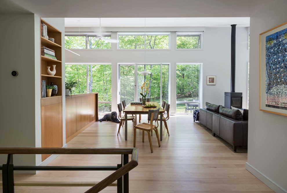 Ispirazione per una sala da pranzo aperta verso il soggiorno moderna di medie dimensioni con pareti grigie, parquet chiaro e stufa a legna