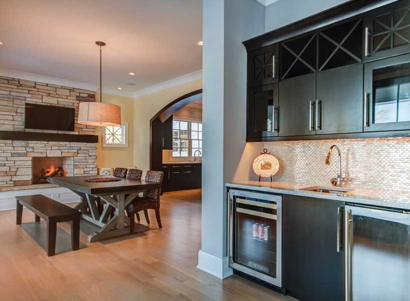 Medium sized contemporary kitchen/dining room in Grand Rapids with yellow walls, light hardwood flooring, a standard fireplace and a stone fireplace surround.