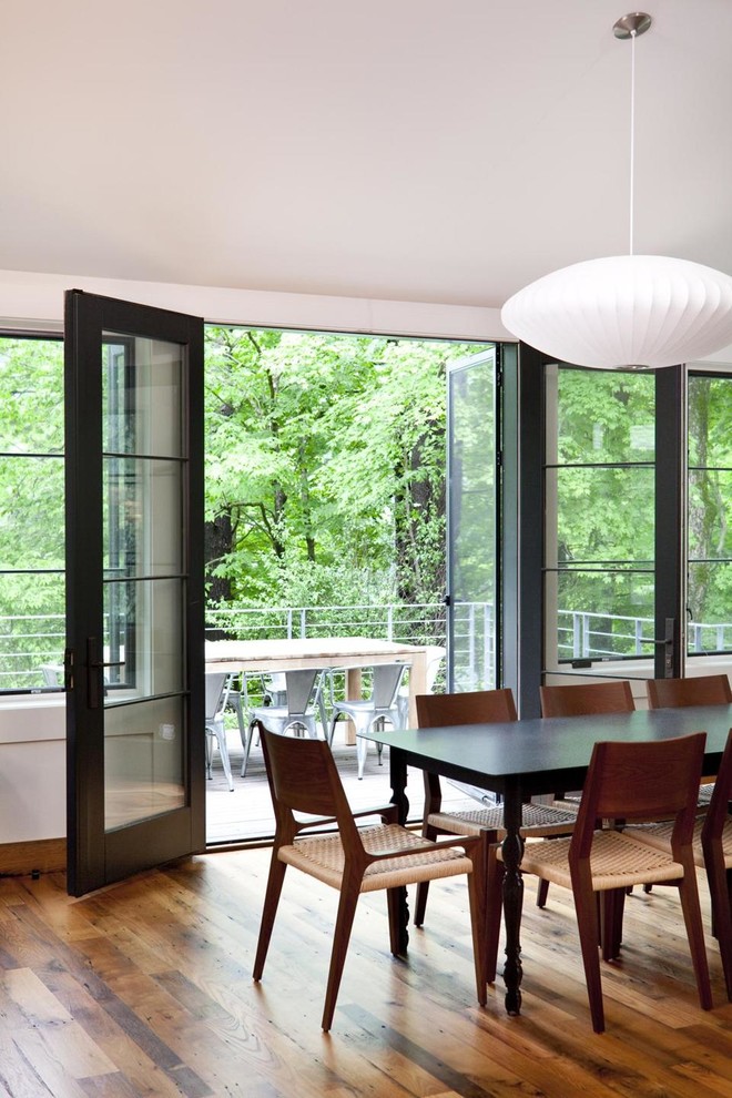 This is an example of a contemporary dining room in New York with dark hardwood flooring.