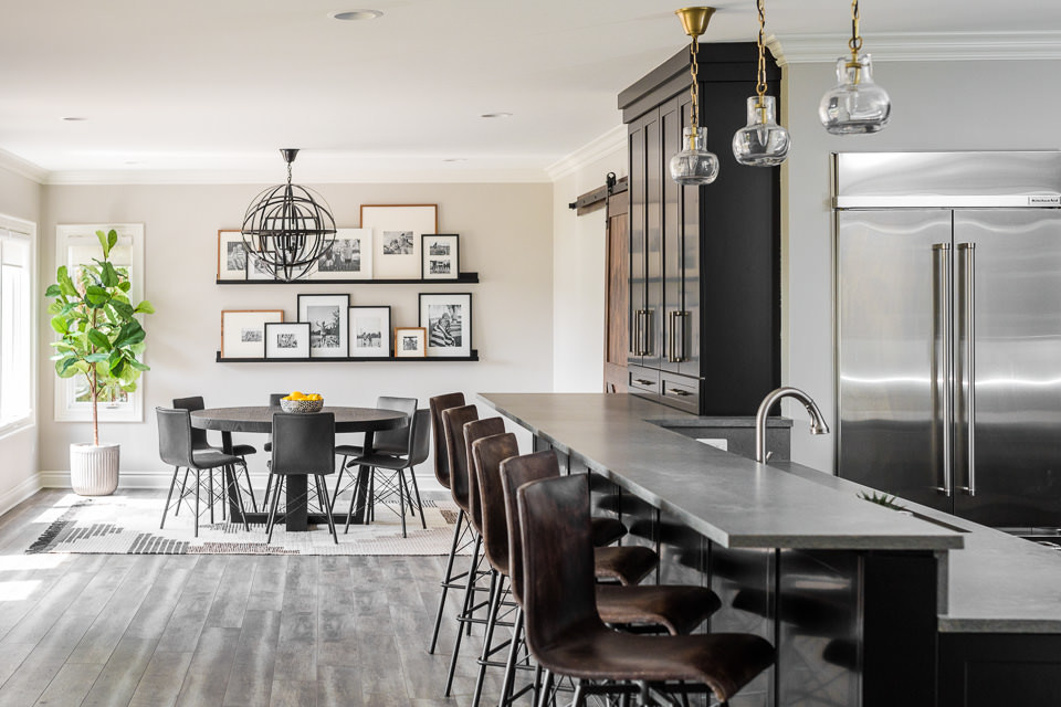 Cette image montre une grande salle à manger ouverte sur la cuisine traditionnelle avec un mur beige, un sol en vinyl et un sol gris.