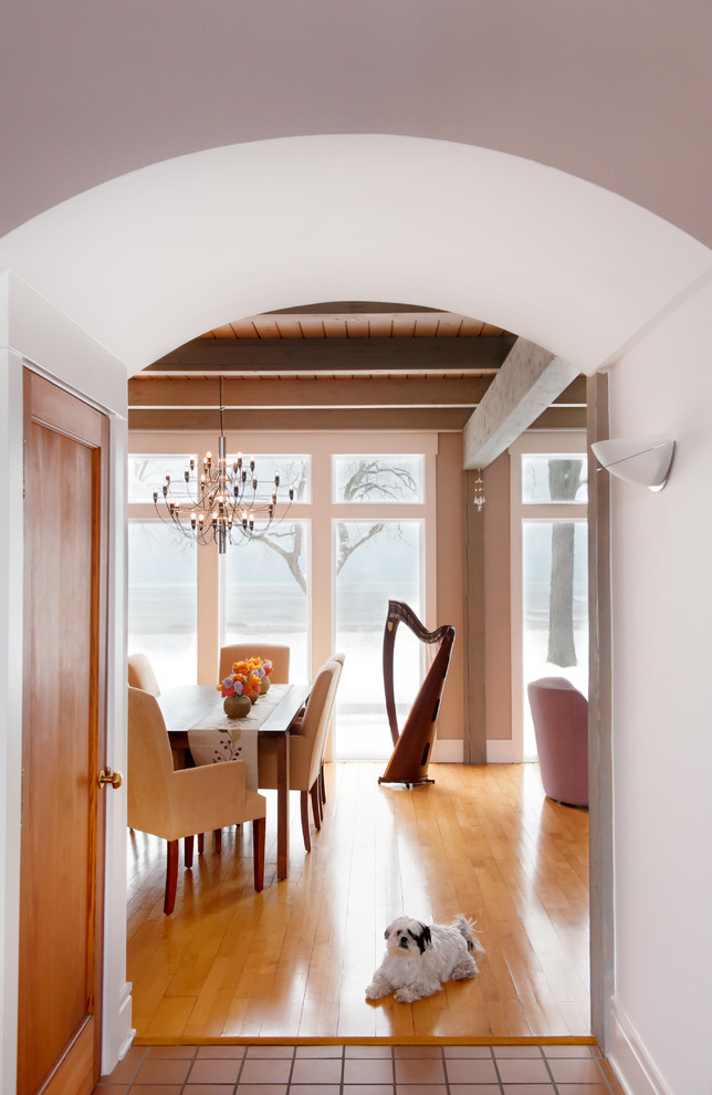 Ejemplo de comedor actual abierto con suelo de madera clara, suelo marrón, vigas vistas y paredes rosas