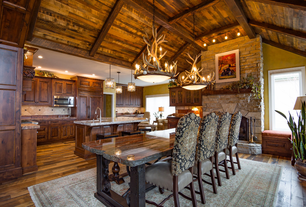 Photo of a large rustic kitchen/dining room in Kansas City with yellow walls, medium hardwood flooring, a standard fireplace and a stone fireplace surround.