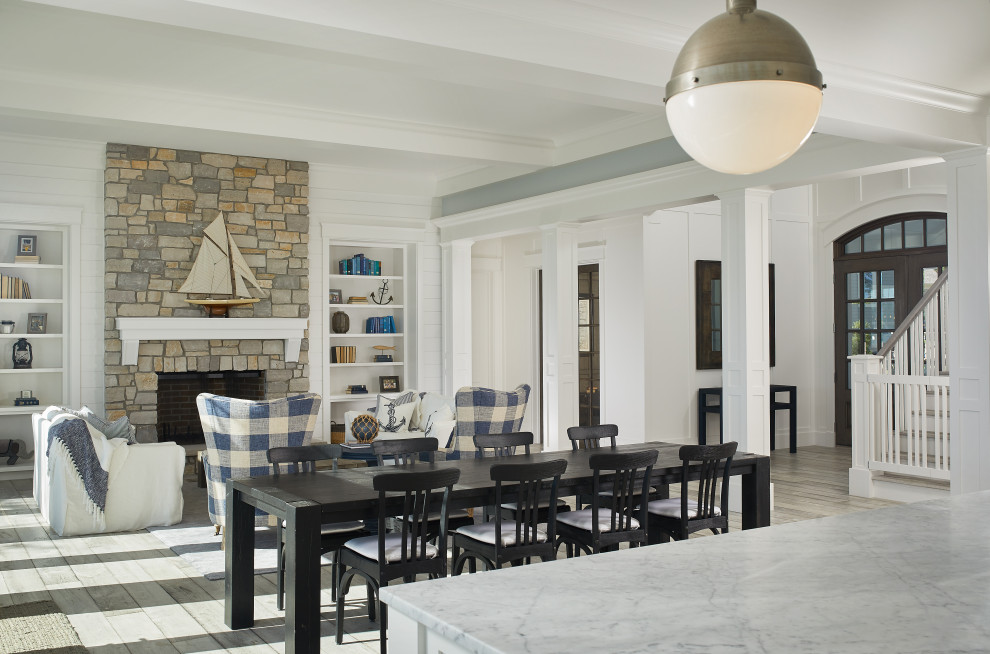 Idée de décoration pour une salle à manger ouverte sur le salon marine avec un mur gris, un sol en bois brun, un sol marron, une cheminée standard, un manteau de cheminée en pierre, un plafond à caissons et du lambris.