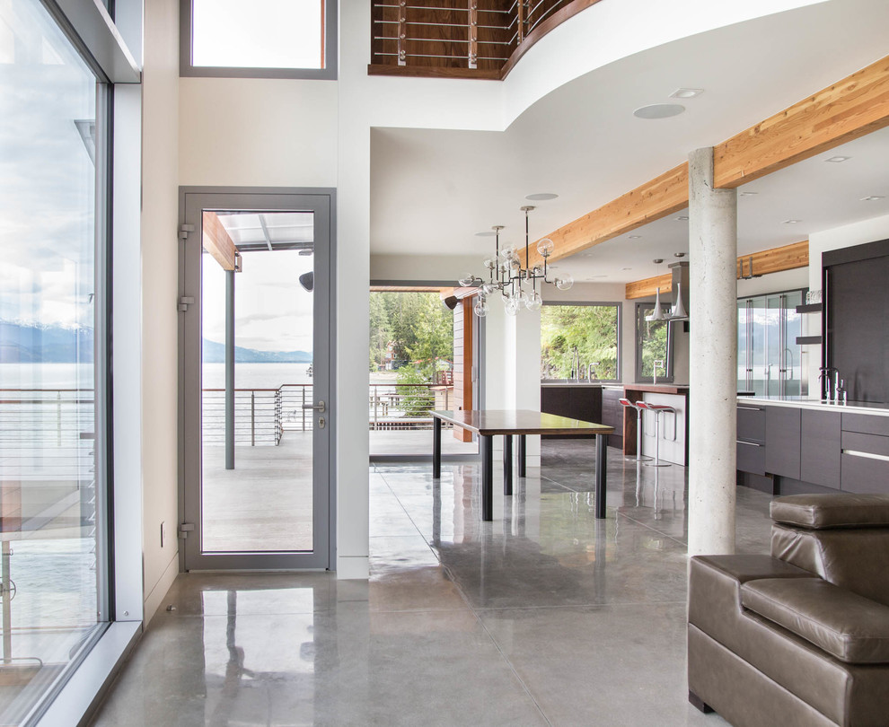 Foto di una sala da pranzo aperta verso il soggiorno contemporanea di medie dimensioni con pareti bianche, pavimento in cemento e pavimento grigio