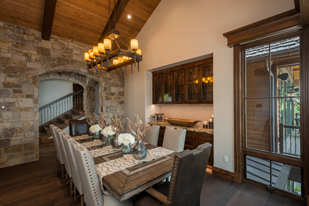 Cette image montre une salle à manger chalet avec un mur blanc, parquet foncé, un sol marron, poutres apparentes, un plafond voûté et un plafond en bois.