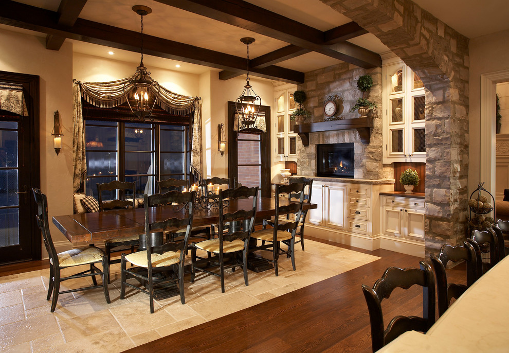 Foto di una grande sala da pranzo aperta verso la cucina chic con pareti beige, pavimento in legno massello medio, cornice del camino in pietra e stufa a legna