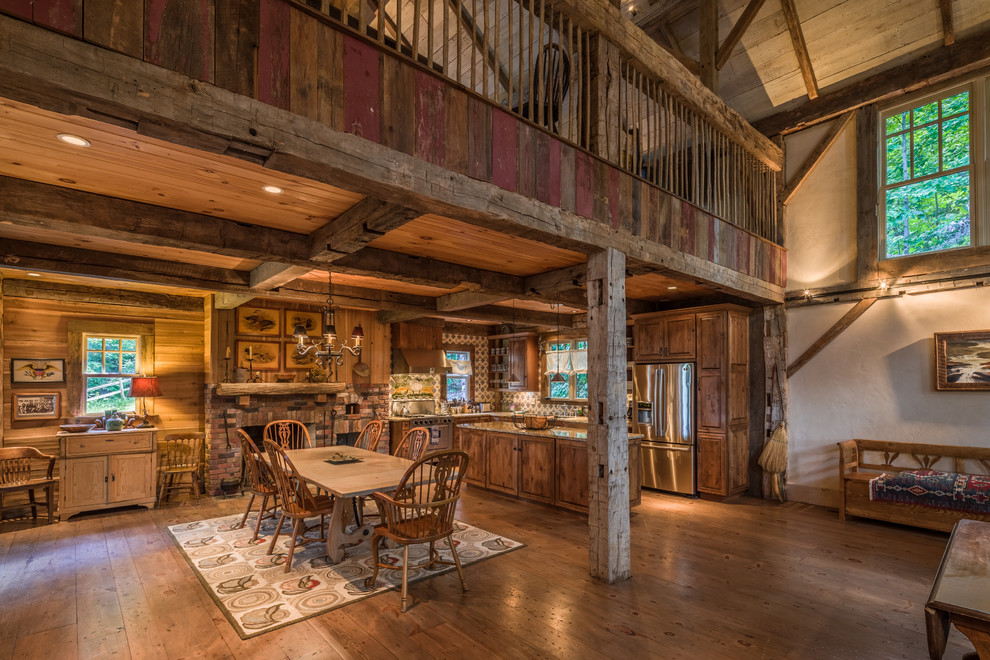 Cette photo montre une salle à manger ouverte sur le salon montagne avec un sol en bois brun, une cheminée standard, un manteau de cheminée en brique et éclairage.