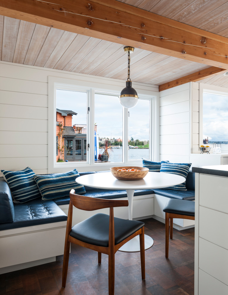 Стильный дизайн: кухня-столовая в морском стиле с белыми стенами, темным паркетным полом, коричневым полом, балками на потолке, деревянным потолком и стенами из вагонки - последний тренд