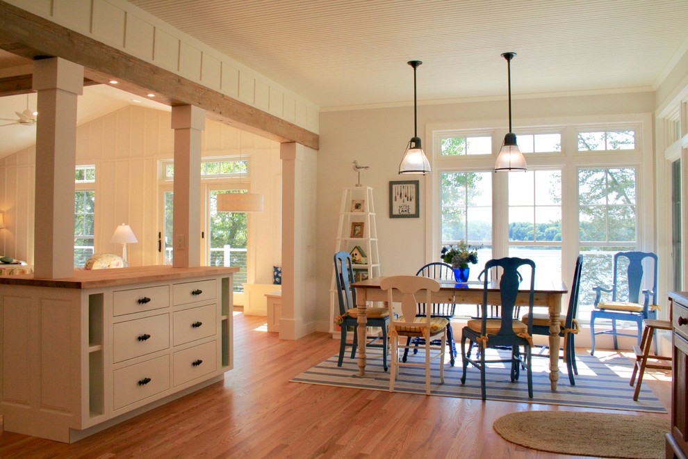 Idee per una sala da pranzo aperta verso il soggiorno stile marinaro di medie dimensioni con pareti bianche, pavimento in legno massello medio e pavimento marrone
