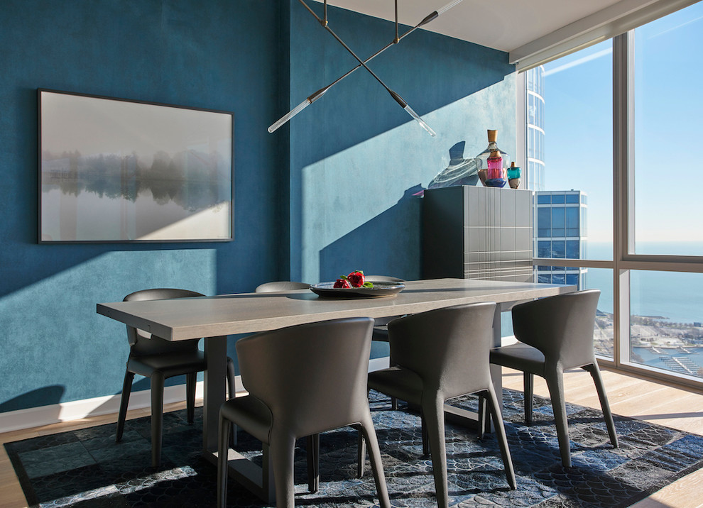 Imagen de comedor contemporáneo con paredes azules y suelo de madera clara