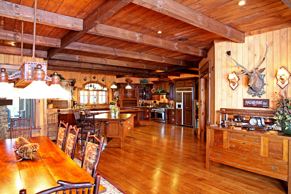 Immagine di una grande sala da pranzo aperta verso la cucina stile rurale con pareti marroni e pavimento in legno massello medio