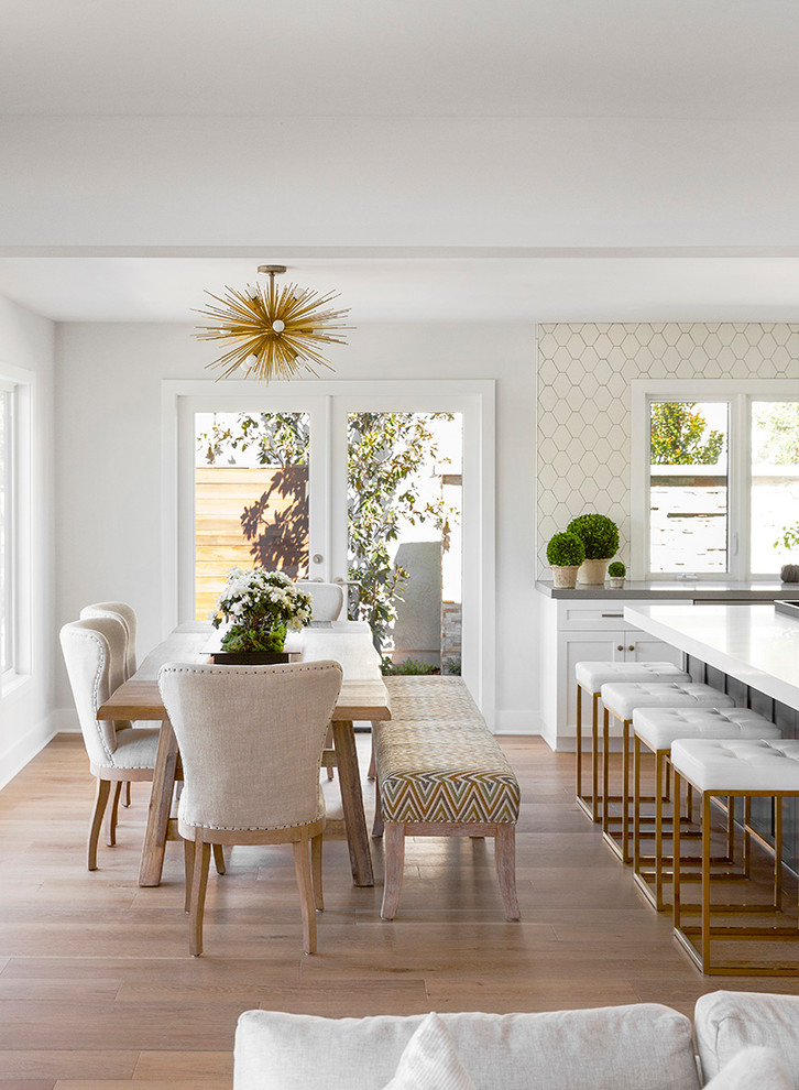 Esempio di una sala da pranzo aperta verso la cucina chic di medie dimensioni con pareti bianche, parquet chiaro e pavimento beige