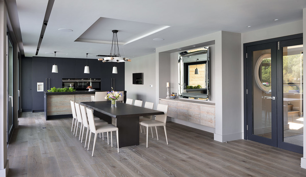 Immagine di una sala da pranzo aperta verso la cucina contemporanea con pareti grigie e pavimento grigio