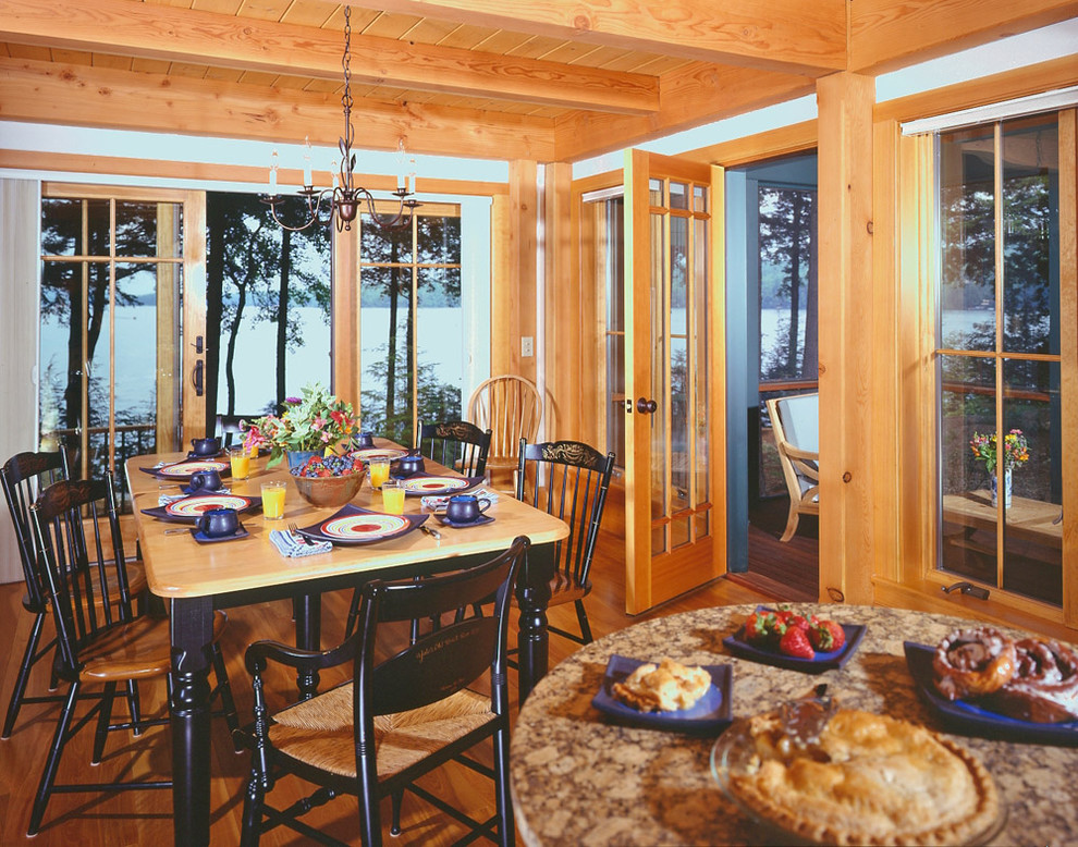 Immagine di una sala da pranzo aperta verso la cucina tradizionale con pavimento in legno massello medio e pareti bianche