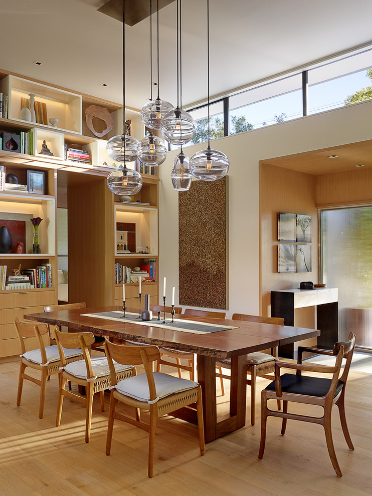 This is an example of a contemporary dining room in San Francisco with white walls and light hardwood flooring.