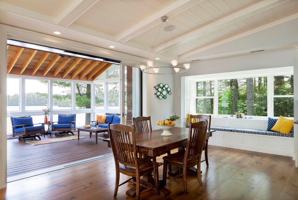 Cette image montre une salle à manger ouverte sur le salon marine avec un sol en bois brun et un mur gris.