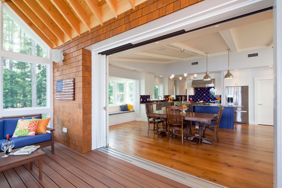 Inspiration pour une salle à manger ouverte sur la cuisine marine avec un sol en bois brun et un mur gris.