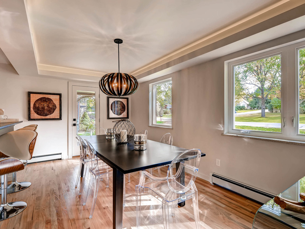 Cette image montre une salle à manger ouverte sur la cuisine design avec un mur gris, un sol en bois brun et aucune cheminée.