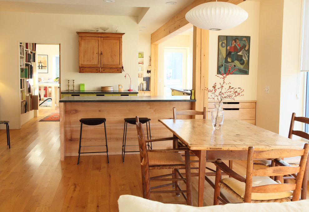 Cette image montre une salle à manger ouverte sur la cuisine minimaliste avec un mur beige et un sol en bois brun.