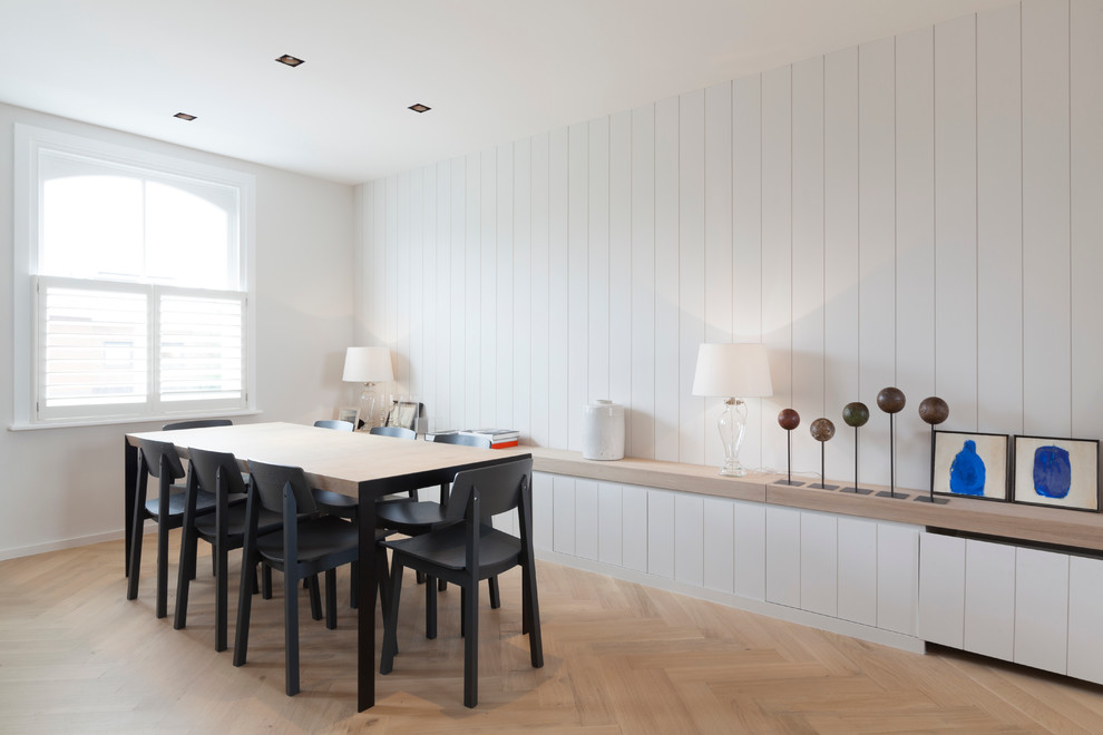Immagine di una sala da pranzo aperta verso la cucina nordica di medie dimensioni con pareti bianche, parquet chiaro e nessun camino