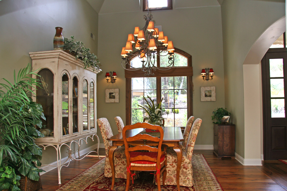 This is an example of a classic dining room in Sacramento with green walls and dark hardwood flooring.