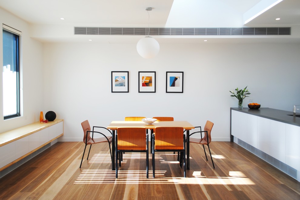 Kleine Moderne Wohnküche ohne Kamin mit weißer Wandfarbe und braunem Holzboden in Melbourne