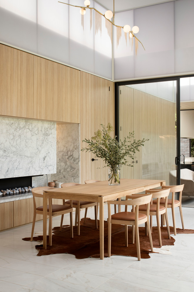 Immagine di una sala da pranzo minimal con pareti beige, camino lineare Ribbon e pavimento grigio