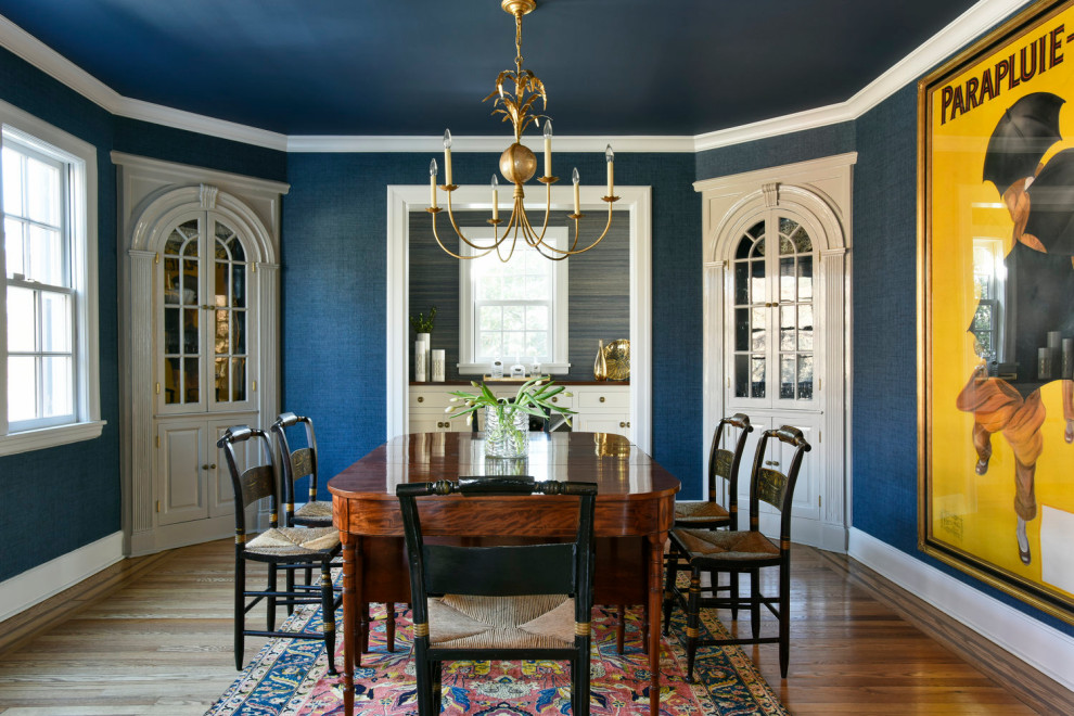 Ispirazione per una sala da pranzo chic chiusa con pareti blu, pavimento in legno massello medio, pavimento marrone e carta da parati