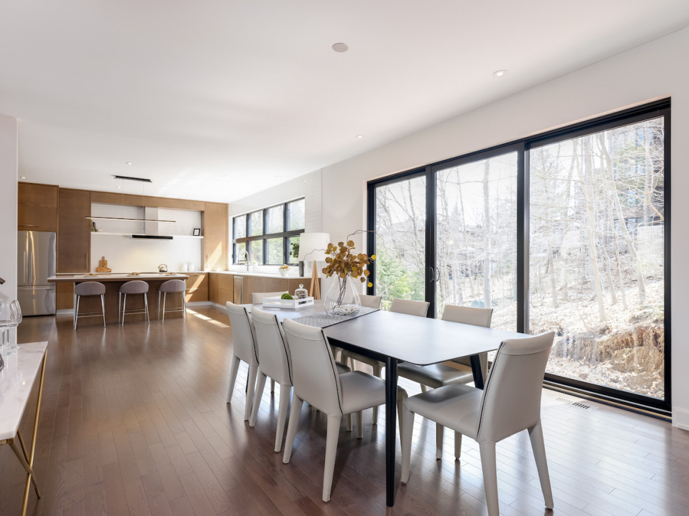 Geräumige Moderne Wohnküche mit roter Wandfarbe, braunem Holzboden, Gaskamin, Kaminumrandung aus Holzdielen, braunem Boden und Holzwänden in Montreal