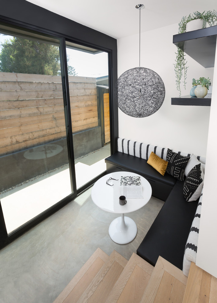 Ispirazione per una sala da pranzo aperta verso il soggiorno design di medie dimensioni con pareti bianche, pavimento in cemento e pavimento beige