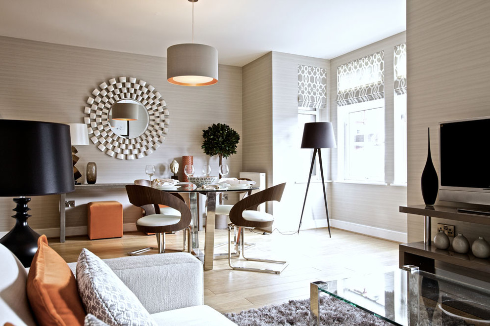 Réalisation d'une salle à manger ouverte sur le salon design avec un mur beige, parquet clair et éclairage.
