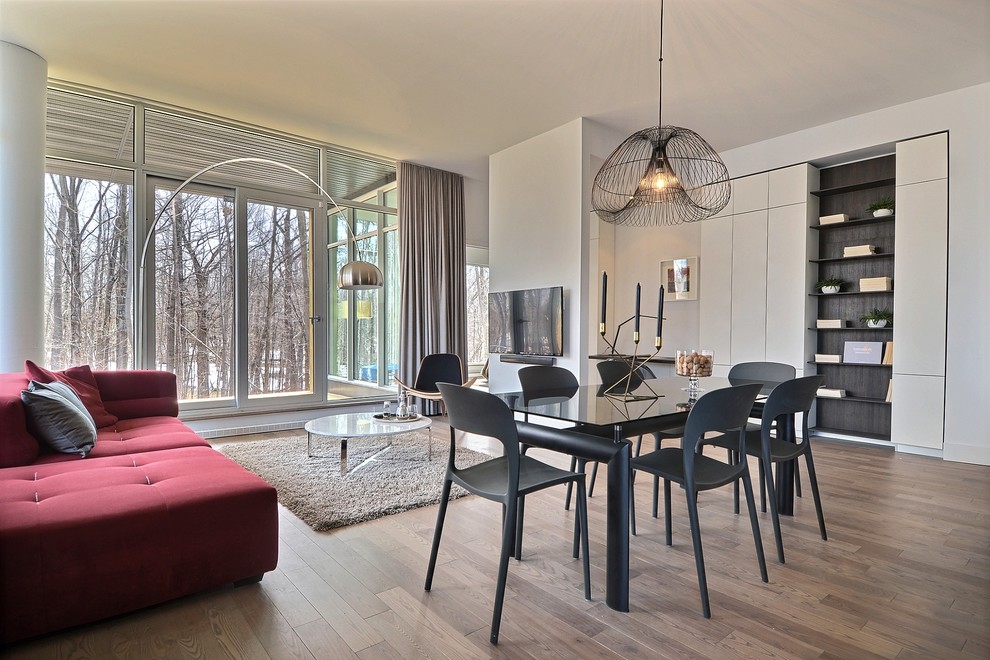 Réalisation d'une salle à manger ouverte sur le salon design avec un mur blanc, un sol en bois brun et aucune cheminée.